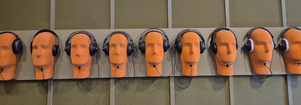 Eine Installation im hätuigen Veranstaltungsraum des MPS-Studio zeigt eine Reihe an Kopfhörern. In diesem Raum standen damals die Musiker*innen und nahmen ihre Musik auf.