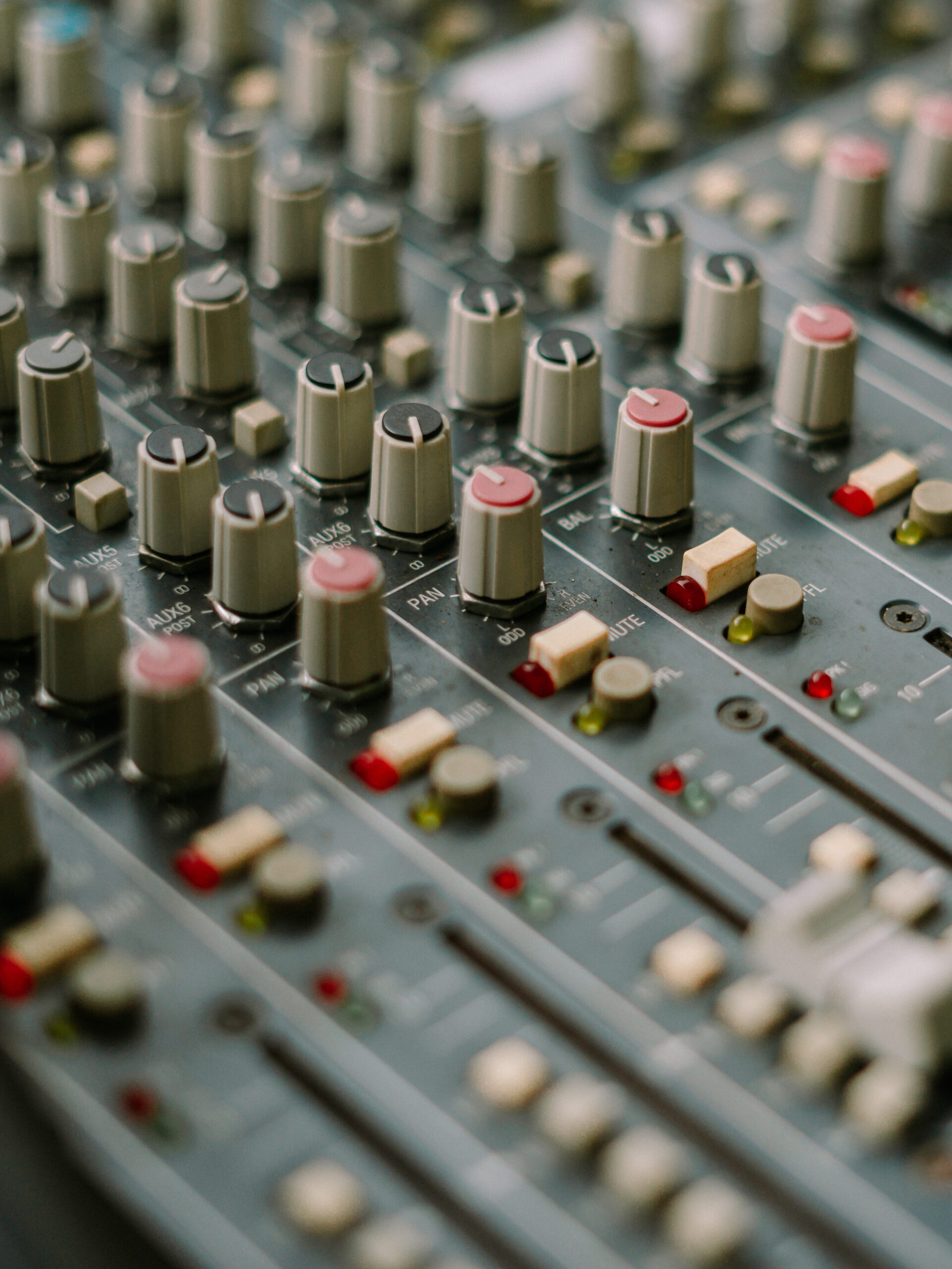 Nahaufnahme eines Audiomischpults mit Reglern und Bedienelementen zur Klangsteuerung.